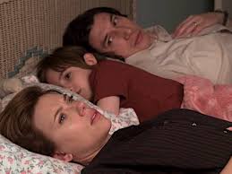 Na imagem extraída do filme: casal está deitado com seu filho numa cama