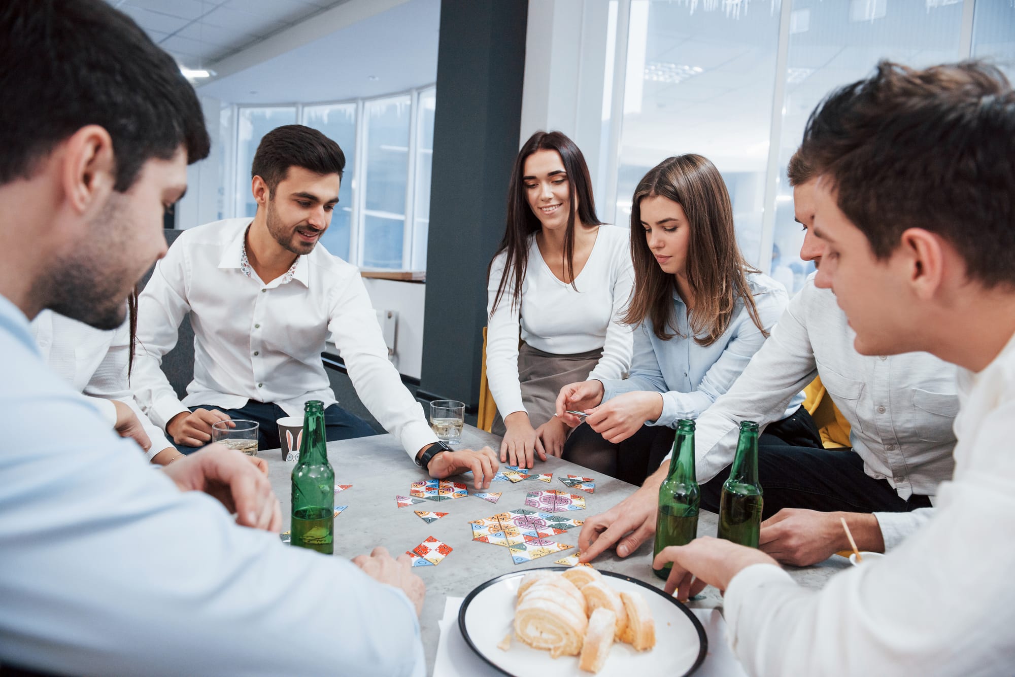 Na imagem, 5 advogados homens e mulheres estão em volta de uma mesa atentos em um jogo de peças.