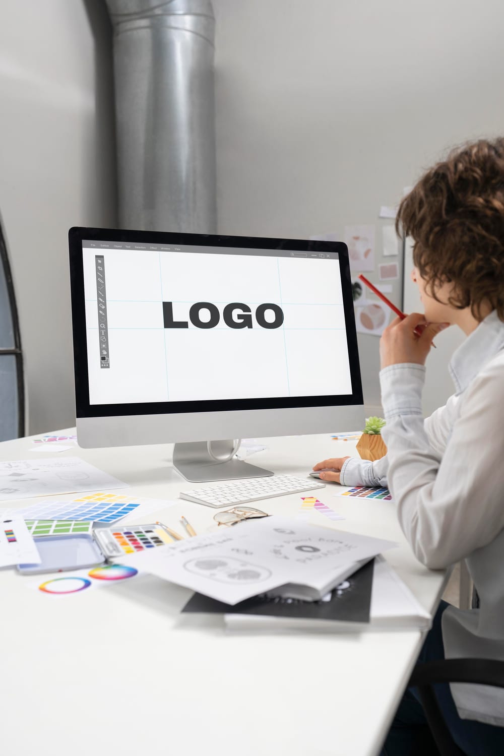 Na imagem: Profissional de criatividade olha para monitor com a palavra "Logo" escrita na tela.