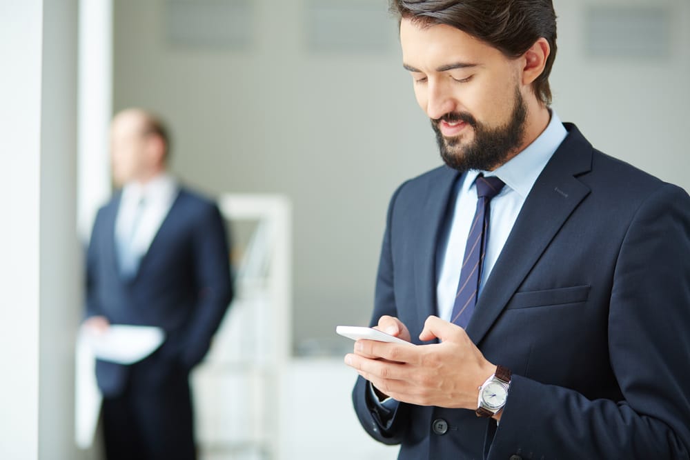 Na imagem: Advogado utiliza celular com semblante de tranquilidade