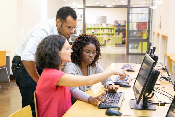 Na imagem: funcionários treinam estudante jovem em frente a um computador 